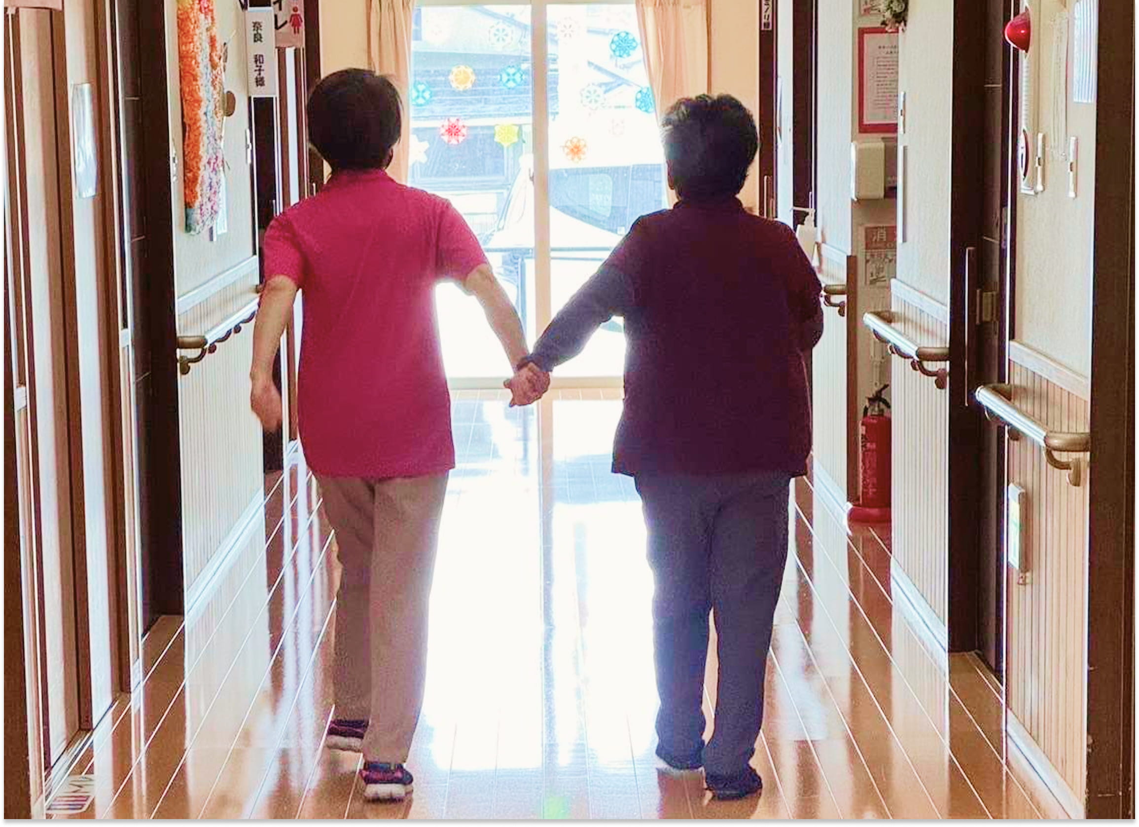 利用者と職員が手を繋いで歩いている写真